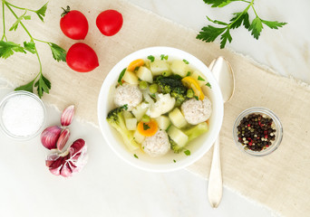 bowl of soup, a cup of broth and vegetables, meatballs made of turkey and chicken, top view