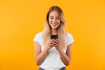 Portrait of a smiling young blonde girl using mobile phone