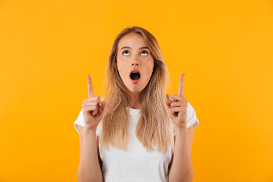 Portrait of a shocked young blonde girl pointing up