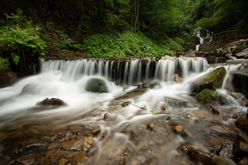 Beautiful mountain rainforest waterfall with fast flowing water and rocks, long exposure.
