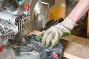 Saw the board. The man saws the board with an electric saw. Joinery.