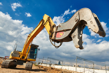 excavator crasher machine with crushing jaws at demolition on construction site