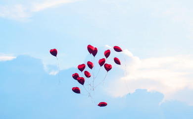 Red balls in the form of a heart fly into the blue sky.