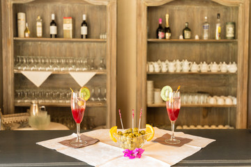 Appetizer. Two red cocktails and a bowl with  olives on the bar counter