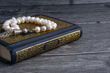 Kuala Lumpur, Malaysia- December 4, 2017: Closeup of Holy Quran/Koran with beads or Tasbih/Rosary over wooden background.Selective focus and crop fragment.