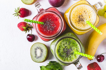 Selection of multicolored fruit smoothies  in glass jars.