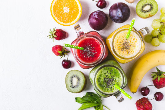 Selection of multicolored fruit smoothies  in glass jars.