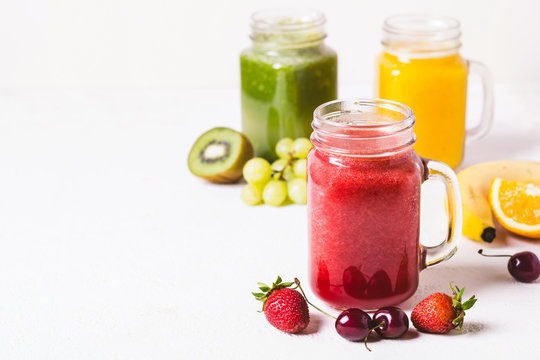 Red, yellow and green smoothie in a glass jar and ingredients