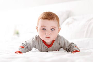 Cute little baby child lies on bed indoors at home.