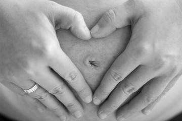 Schwangere Frau mit geformtem Herz aus Händen