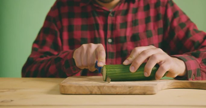 Young man cutting cucumber