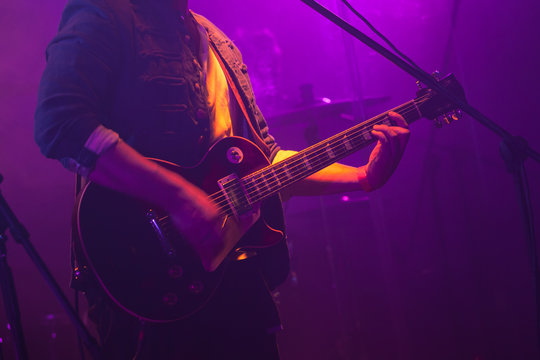 Guitarist plays on guitar in purple lights