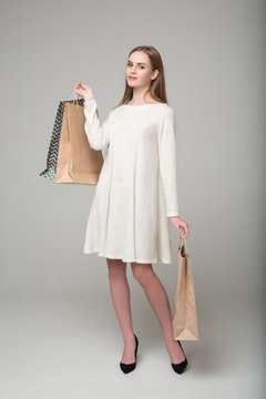 Blond woman in white short dress with shopping paper bags