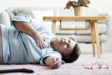 Grandmother with heart attack lying on the floor alone at home