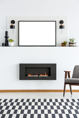 Mockup of empty white poster above fireplace in flat interior with patterned carpet and armchair. Real photo