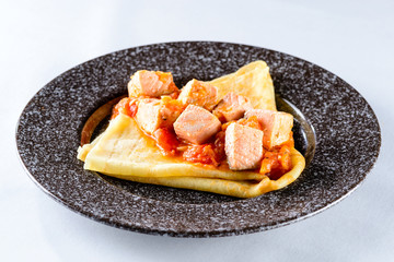Delicious pancake blini with salmon and sauce on light backgroun