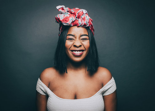 Portrait of happy woman wearing head tie over gray background