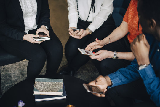 Low section of business people using mobile phones while sitting at conference