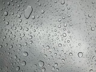Rain drops on window glasses surface with cloudy background Natural Pattern of raindrops isolated on cloudy background 