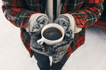 Person in winter clothes holding hot coffee