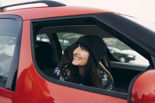 Smiling woman looking away while sitting in red car