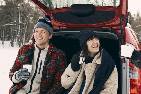 Friends Sitting In Back Of Car Drinking Coffee