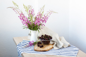rustic still life: wildflowers in a vase and cherry on a wooden table