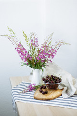Delicious burgundy large cherry in an aluminum mug on the table. Still-life in the rustic style