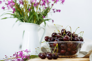 rustic still life: wildflowers in a vase and cherry on a wooden table