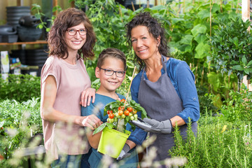 Mutter mit Sohn in der Gärtnerei beim Tomatenpflanzen kaufen