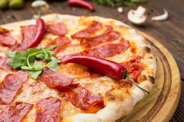 Pizza pepperoni with mozzarella cheese, salami and arugula on wooden background