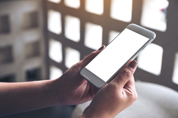 Mockup image of woman's hands holding white mobile phone with blank desktop screen in cafe