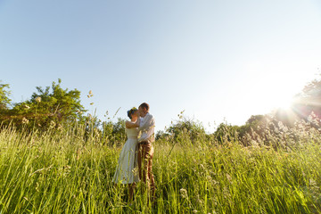 Naklejka na ściany i meble Young wedding couple enjoying romantic moments in field.
