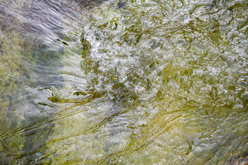 Pure mountain water flowing over mineral stones and rocks, refreshing and calming nature atmosphere with water flow, natural water detail and close up