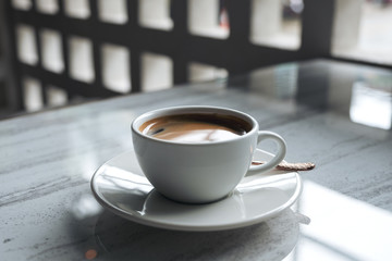 Closeup image of a white cup of hot coffee on table in cafe