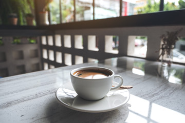 Closeup image of a white cup of hot coffee on table in cafe
