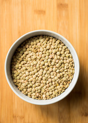 White ceramic bowl of green uncooked lentils