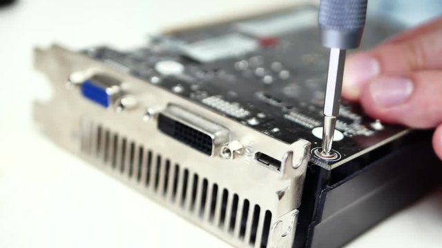 Computer repair. Professional master in service center for computer repair screw the screw with screwdriver on circuit board. Concept of computer hardware, repairing, upgrade and technology