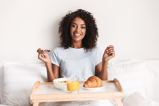Happy young african woman having tasty breakfast