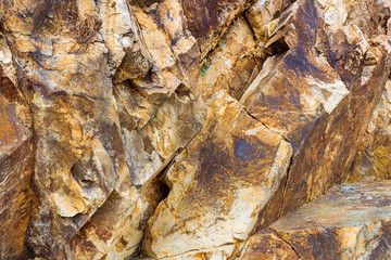 Brown stone texture. Rock formation with cracks and protrusions. Mountain of castle San Juan. Spanish beach resort Blanes in summertime, Costa Brava, Catalonia, Spain