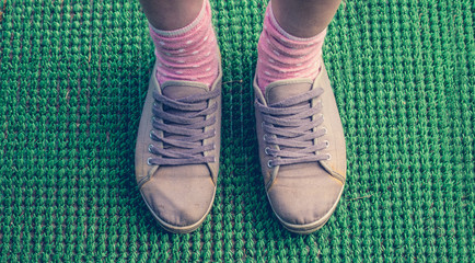 Gray sneakers on female legs on a green background
