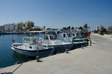 Fototapeta na wymiar Fishing motor boats tied with rope to pier in boat station, Cyprus