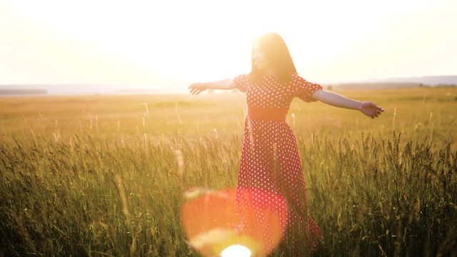 slow motion video. beautiful girl whirls in the field hands in the hand silhouette at lifestyle sunset sunlight. woman concept freedom joy happiness travel