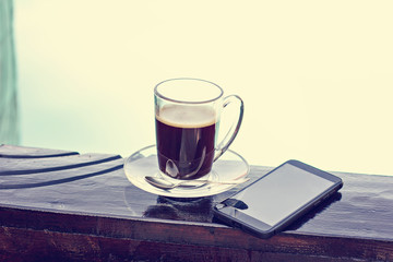 A cup of espresso and mobile phone and a pool in the background. Morning coffee. Summer Breakfast.