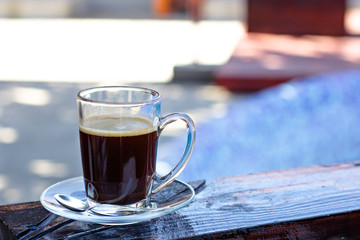 A cup of espresso and a pool in the background. Morning coffee. Summer Breakfast.