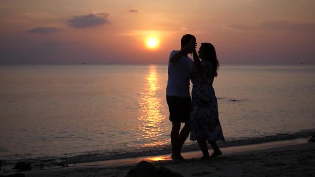 A happy man and woman whirl in a dance on the beach and a beautiful sunset. HD, 1920x1080, slow motion