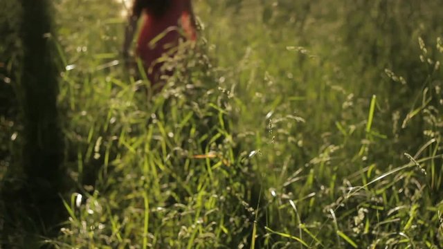 Little girl running joyfully among green grass, spends leisure relaxing in field
