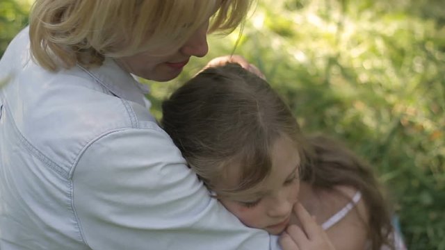 Happy family. Attractive mom patting on head her sleeping child outdoor.