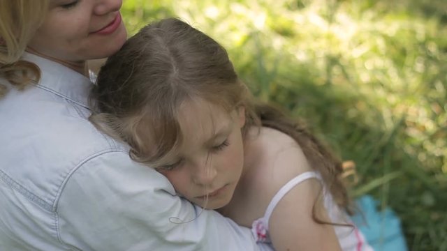 Lovely mom patting on hair her dozing child outside. Happy motherhood. 