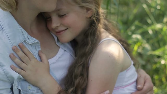 Smiling, cute, kid is close to her mother, sitting in garden, becalming